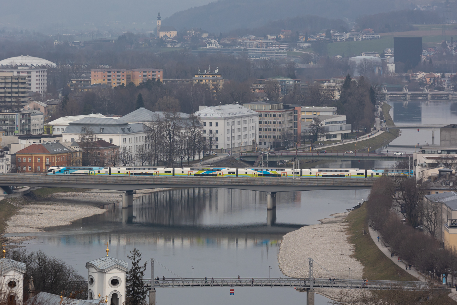 Ein Westbahnzug verlässt Salzburg über die Salzach nach München. 12.2.23
