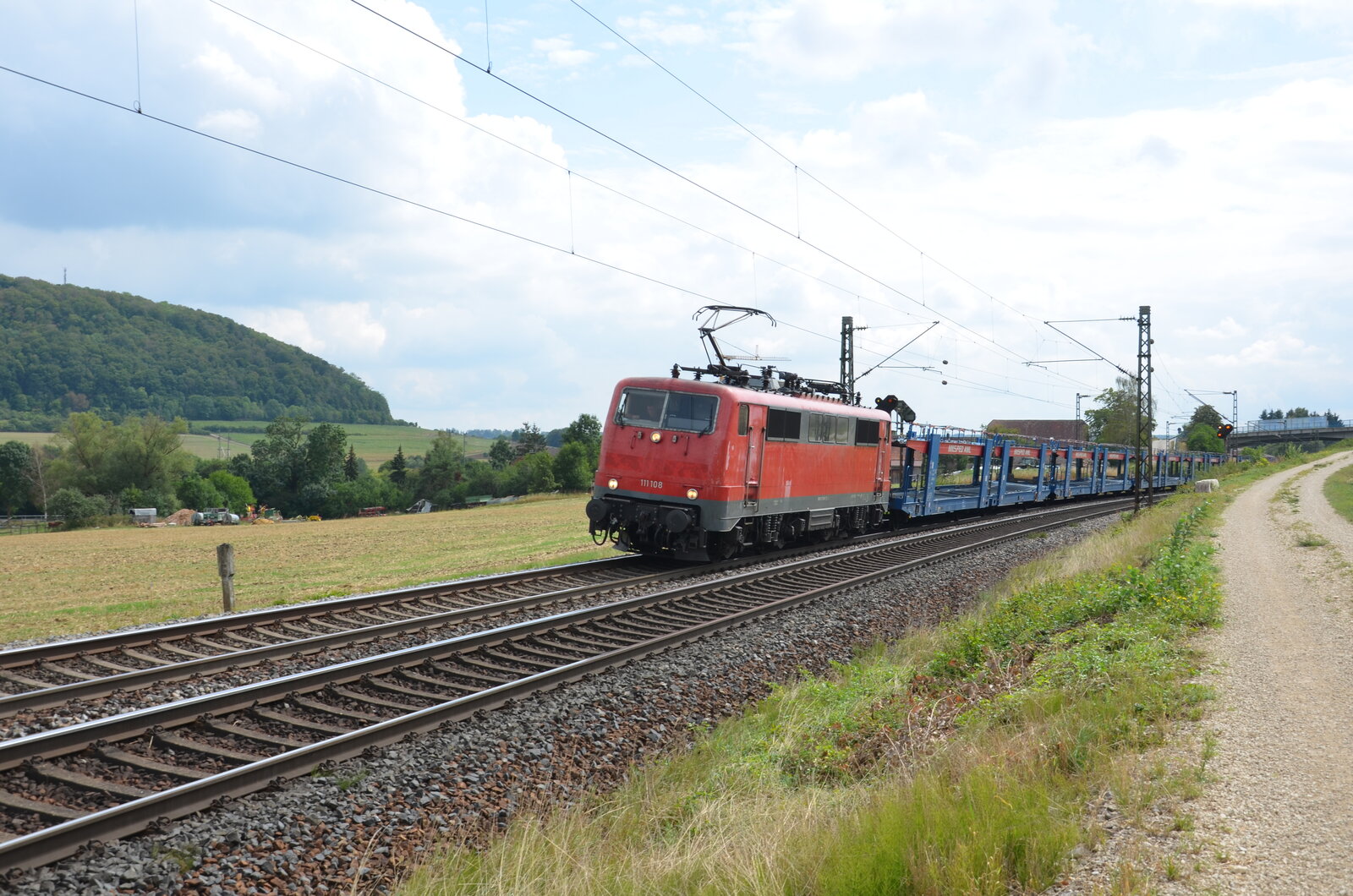 Eine Lok der Baureihe 111 (111-108-x) zieht einen Leerwagenpark bestehend aus Autozugwaggons in Richtung Ansbach. Aufgenommen am 28.08.2022 in der Nähe von Treuchtlingen