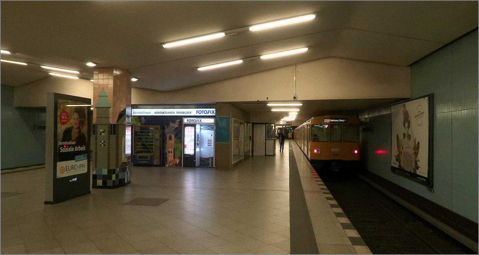 Geheimnisse der Berliner U-Bahn -

Schon beim Bau der U9 in den 1950iger Jahren wurde der Bahnhof Turmstraße als Turmbahnhof für eine hier kreuzende U-Bahnlinie vorbereitet. So sollte die heutige U5 hier die U9 kreuzen. Dafür wurde in der -1 Ebene ein Teil des Bahnsteiges mitgebaut. Man kann dies in der Station der U9 erkennen: da wo die Decke gerade verläuft befindet sich der obere Bahnsteigteil. Die Kreuzung würde jeweils etwa in Bahnsteigmitte wo eine Treppenanlage die beiden Bahnsteige auf kürzestem Weg miteinander verbunden hätten. Ein Treppenaufgang würde sich dort befinden, wo sich unter anderem der Fotoautomat befindet. Von dort ginge es dann auf ein Zwischenpodest und dann nach rechts und links weiter zum U5-Bahnsteig. Teile der Treppe wurde inzwischen für einen weiteren Ausgang zugänglich gemacht.

In ferner Zukunft könnte die U5 hier noch Wirklichkeit werden, allerdings wird hier demnächst eine neue Straßenbahnstrecke vom Hauptbahnhof her kommend den U-Bahnhof Turmstraße erreichen.

14.07.2023 (M)