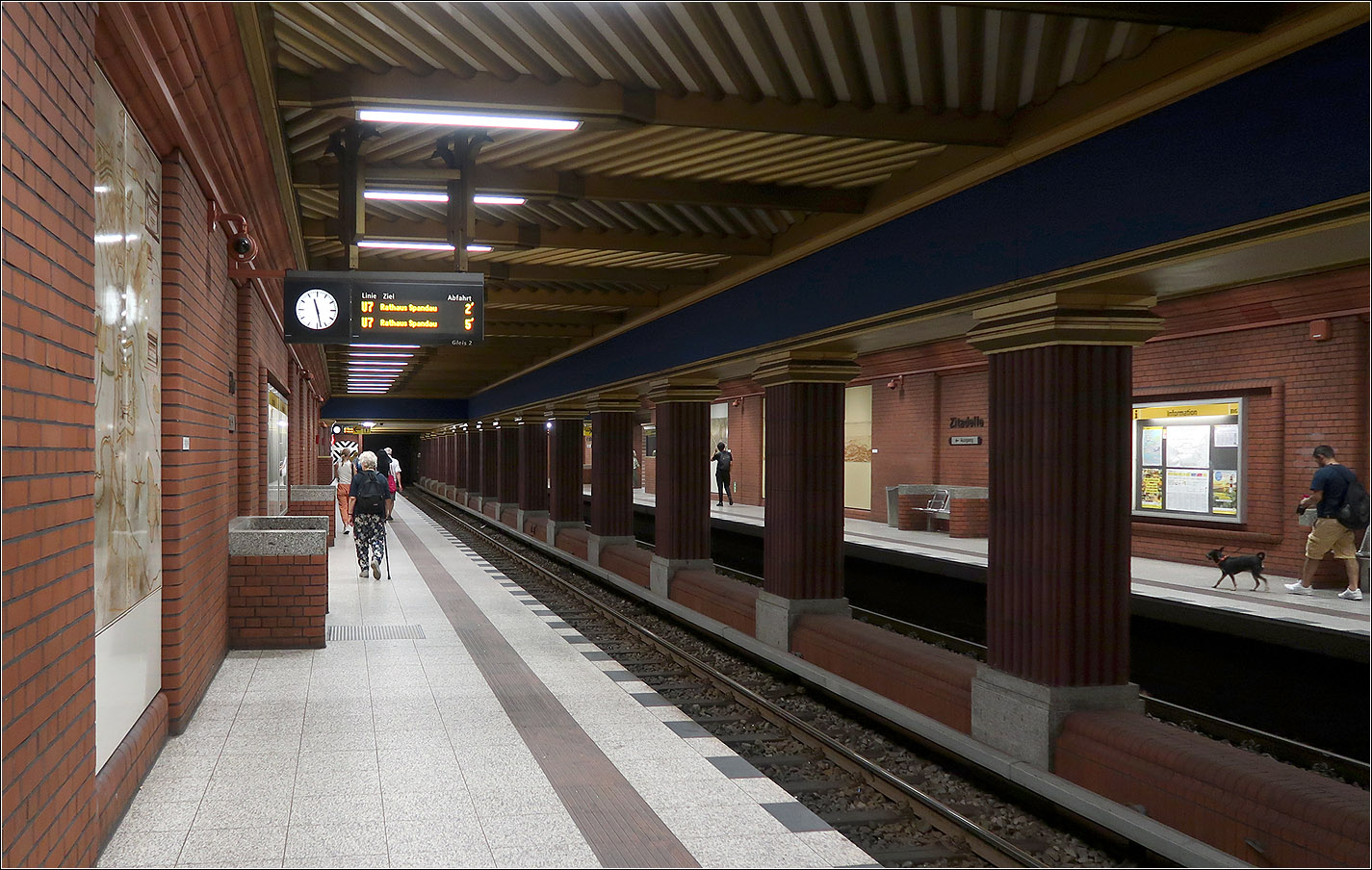 Geheimnisse der Berliner U-Bahn - 

Warum hat der U-Bahnhof Zitadelle Seitenbahnsteige, als einziger U-Bahnhof entlang der U7?
Da der westlich anschließende Streckentunnel mit Havelunterquerung in der Caisson-Bauweise erstellt werden sollte, wäre eine Aufweitung des Streckentunnels für eine Absenkung sehr ungünstig gewesen. Bei dieser Bauweise sollte der Querschnitt gleich bleiben. Auch verringert sich so die Auttriebsfläche des Bauwerks.  
Die Verwendung von Ziegel zur Verkleidung der Bahnsteigwände stellt einen Bezug zur Spandauer Zitadelle her, zu der man hier aussteigen kann.

14.07.2023 (M)