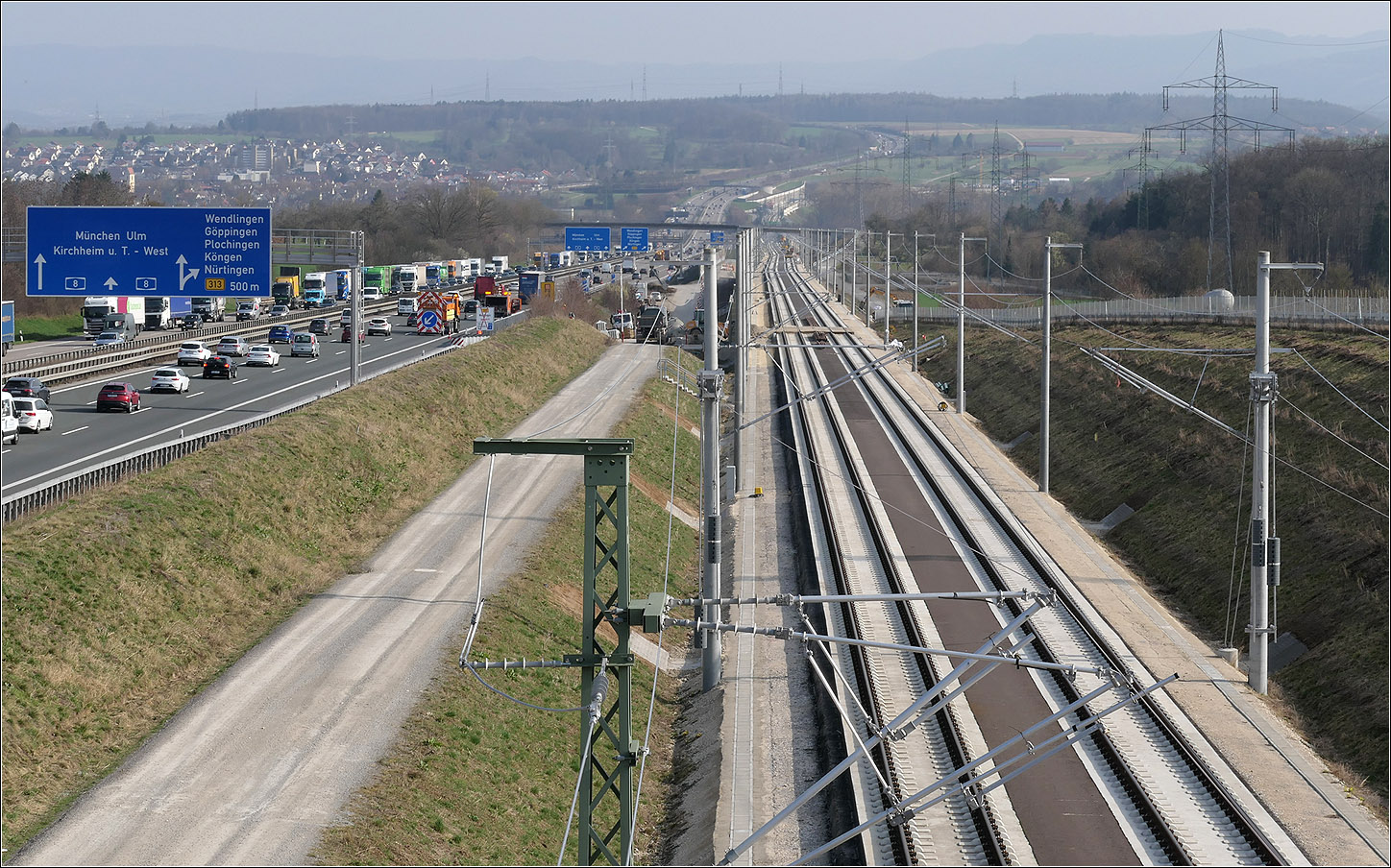 Gemeinsame Neckartalabfahrt - 

... von Autobahn und Eisenbahn, beide für höhere Geschwindigkeiten gedacht. Bei der Bahn wird man diese eher einhalten können. Im weiteren Verlauf der Autobahn im Hintergrund ist keine Schnellfahrstrecke mehr zu sehen, da diese dort im 8174 m langen Albvorlandtunnel verschwunden ist. Ein Gleis dieses Tunnels ist schon in Betrieb.

Oben im Hintergrund ist die Schwäbische Alb im Dunst zu erkennen, die beide Verkehrswege erklimmen müssen.

29.02.2024 (M)