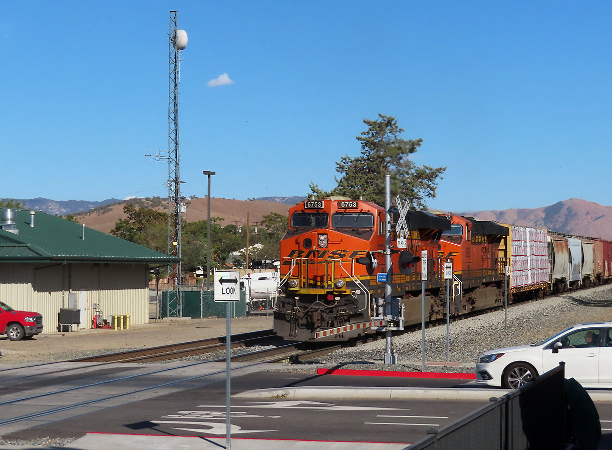 Gemischter BNSF-Güterzug passiert mitten im Städtchen Tehachapi einen Bahnübergang und fährt anschliessend westwärts den Pass hinunter in Richtung Bakersfield. Tehachapi, CA, 25.9.2022