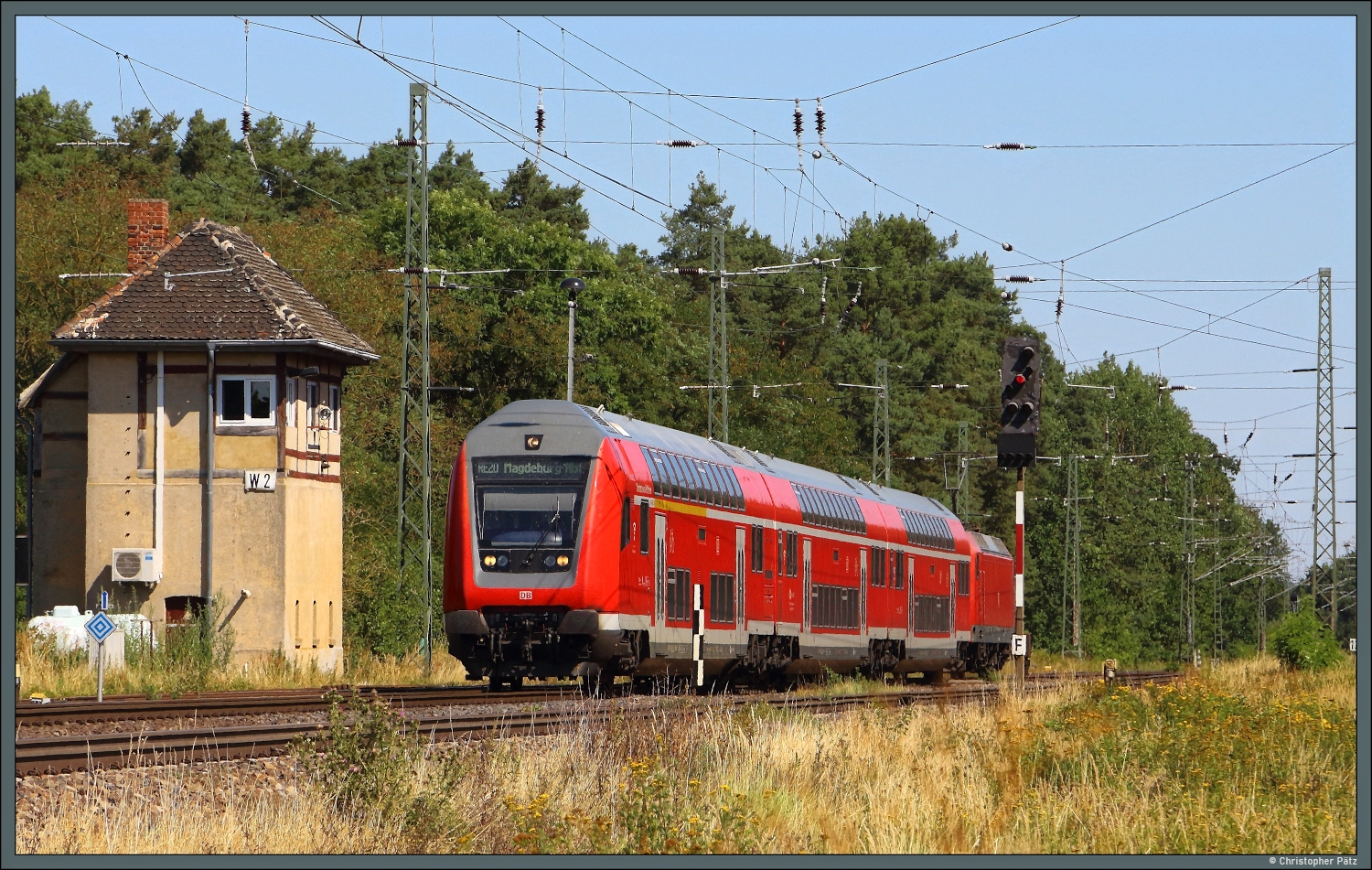 Geschoben von 146 012 der DB Regio passiert am 09.08.2026 ein Doppelstockzug als RE 20 das Stellwerk W 2 im Nordkopf des Bahnhofs Angern-Rog�tz.