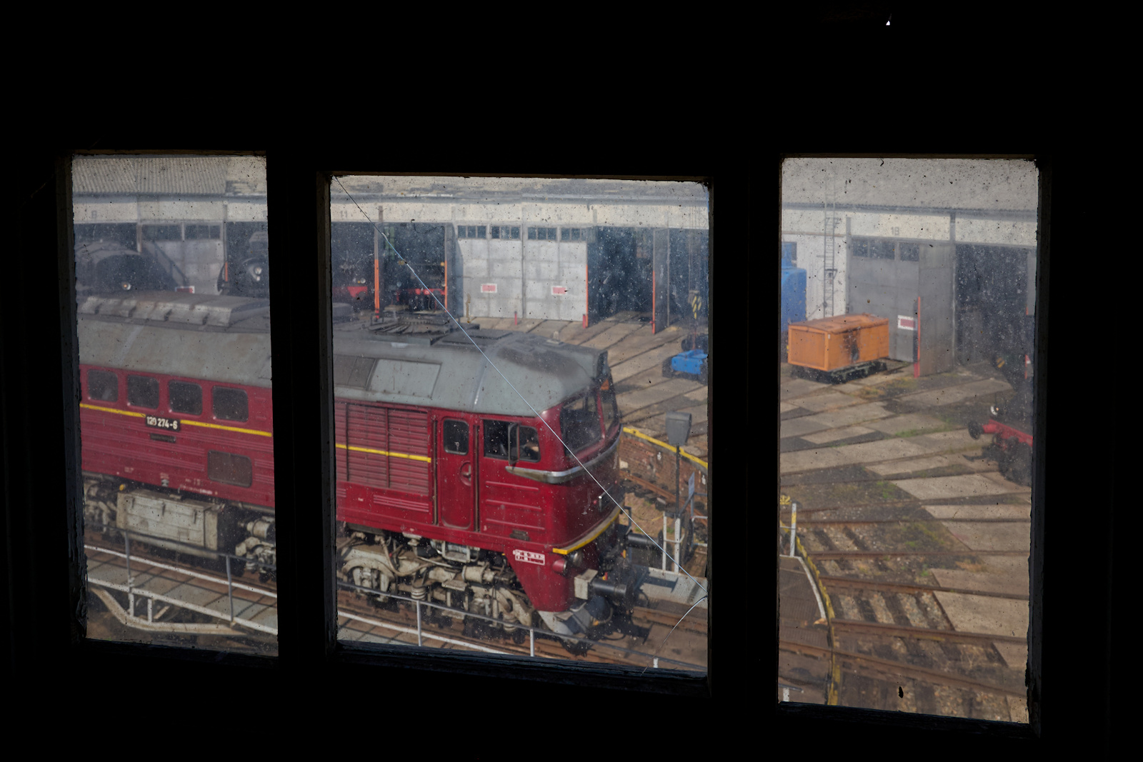 Getr�bter Ausblick: Das alte und kaputte Fenster in der Lokleitung des Bw Arnstadt gibt den Blick frei auf 120 274, die auf der Drehscheibe steht.
