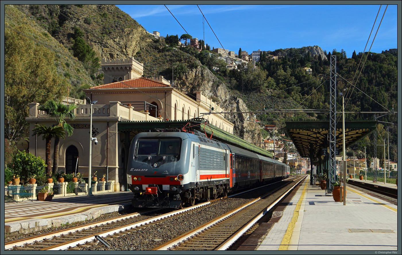 Gezogen von E464 373 und mit E464 264 am Zugschluss hat der ICN 1959 Rom - Siracusa am 26.02.2024 den gepflegten Bahnhof Taormina-Giardini erreicht. Das deutlich höher gelegene Stadtzentrum des Ortes ist oberhalb des Zuges zu erkennen.
