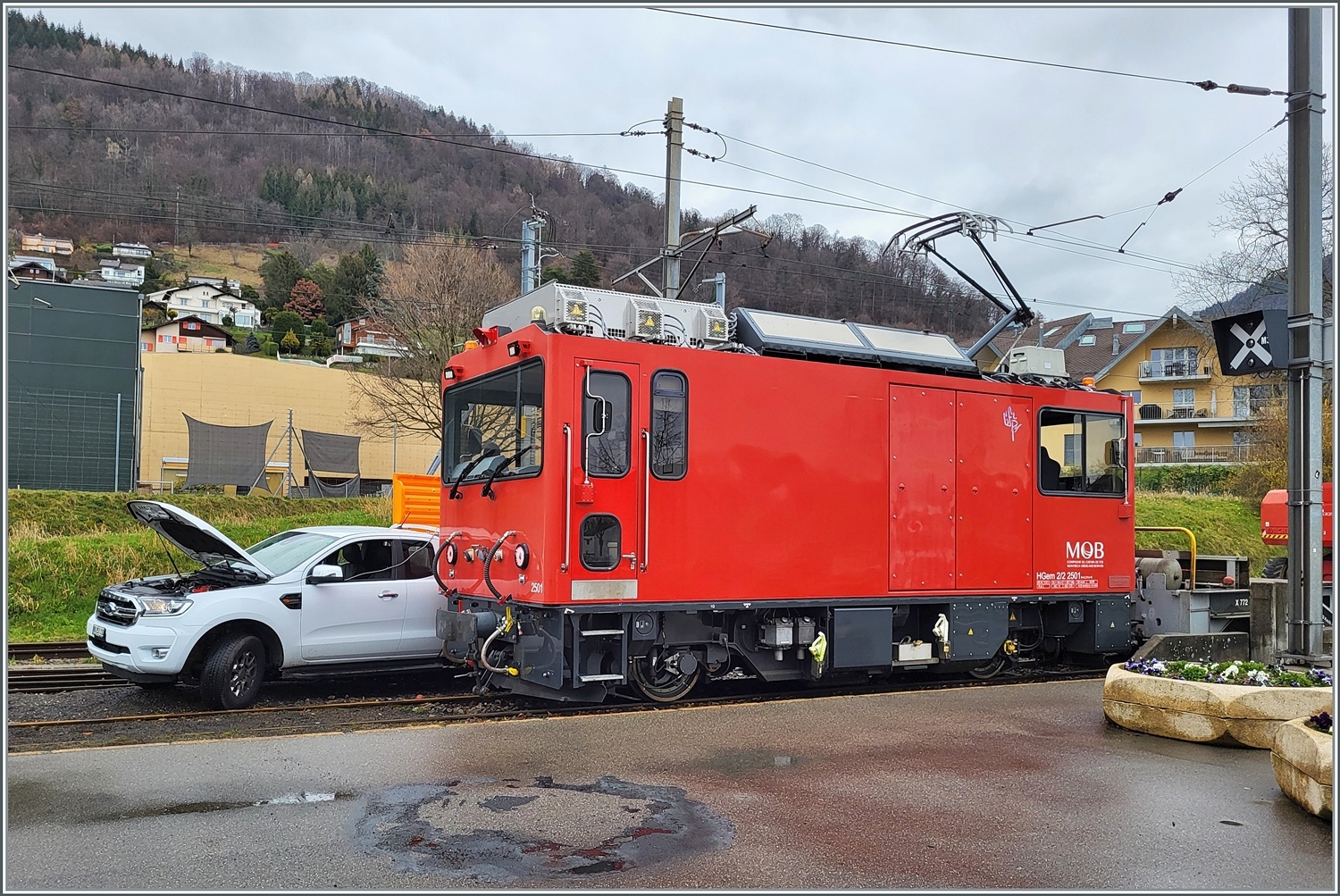 HGem 2/2 2501 nennt sich die Lok im Vordergrund; und das Auto mitten auf den Schienen im Bahnhof von Blonay kümmert sich um das  m  in der Lokbezeichnung: Die Lok wird betankt!
 
1. März 2024