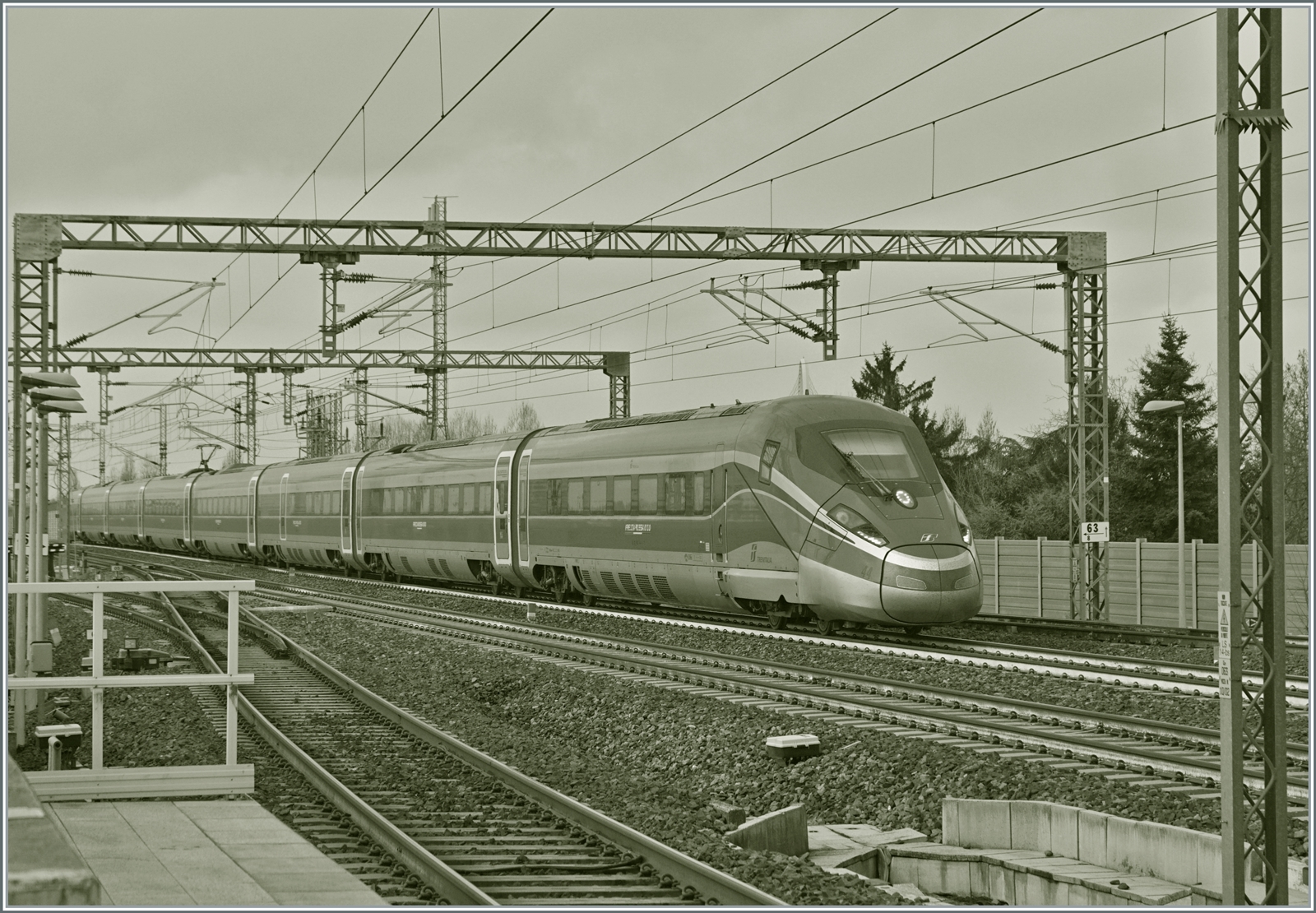 High speed in S/W: Der FS Trenitalia ETR 400 044 ist als  Frecciarossa 1000  FR 9623 von Milano Centrale nach Roma Termini unterwegs und fährt mit einer beachtlichen Geschwindigkeit durch den Bahnhof von Reggio Emilia AV. 

14. März 2023