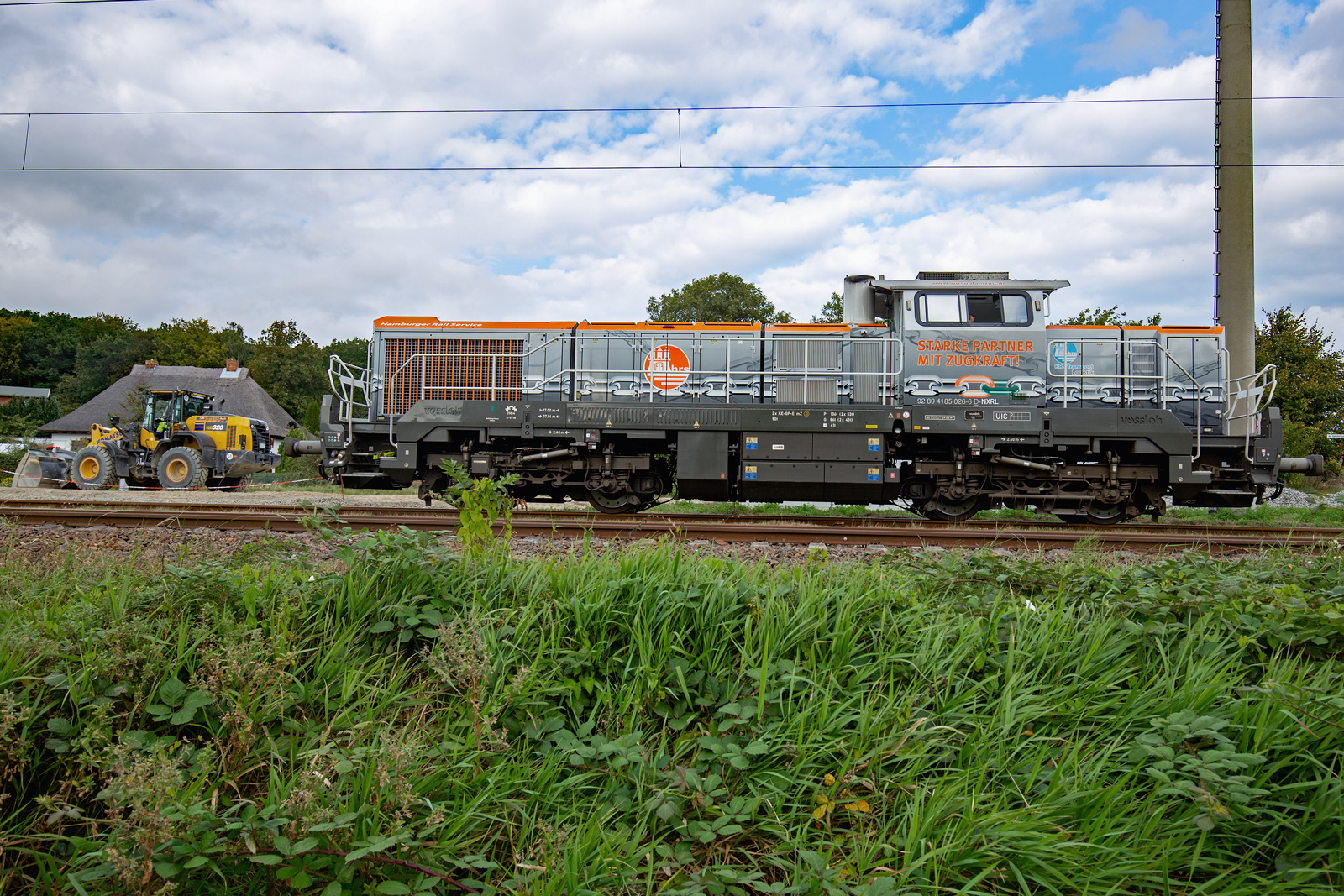 Lok von VOSSLOH der Baureihe 185 wartet gemeinsam mit einem KOMATSU RADLADER WA 320 in Lancken auf den nächsten Bauzugeinsatz. - 23.09.2023