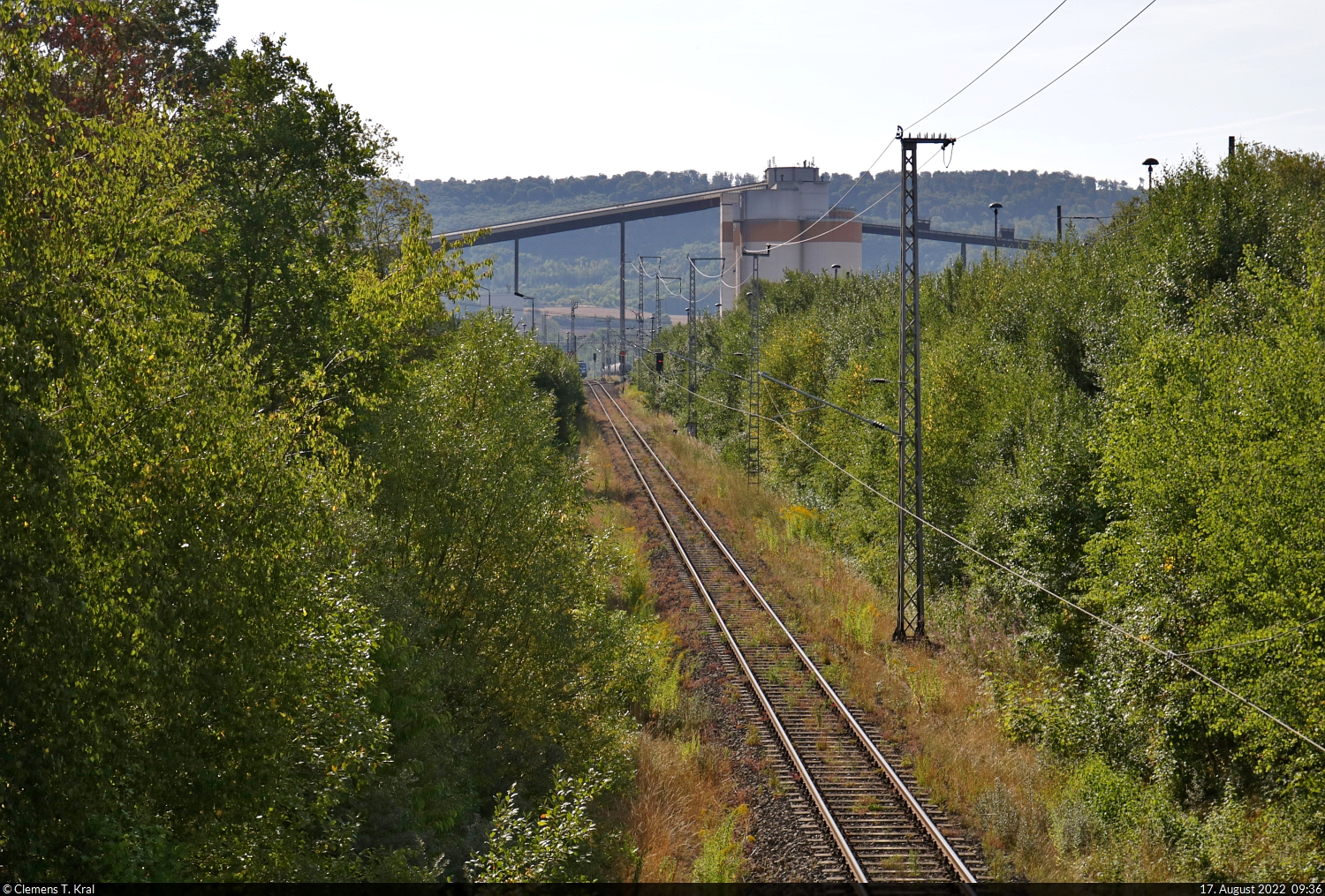 Mit dem Fahrrad von Kassel nach Halle (Saale) | Tag 3 Bernterode–Görsbach
Anschlussbahn Zementwerk Deuna

Am Morgen des dritten Tages ist der Werksanschluss der Deuna Zement GmbH (Dyckerhoff GmbH) die erste Station. Das knapp vier Kilometer lange Gütergleis zweigt vom Bahnhof Bernterode ab und mündet in ein etwa 25 Kilometer langes Werksbahnnetz zum Zusammenstellen der Zementzüge. Leider ist während des Kurzbesuchs nichts los, sodass eine Aufnahme der Strecke unmittelbar vor dem Zementwerk genügen soll.
Viel Zeit zum Warten gibt es nicht, denn mit rund 70 Kilometern wird dies die längste und anstrengendste Tagestour.

🕓 17.8.2022 | 9:36 Uhr