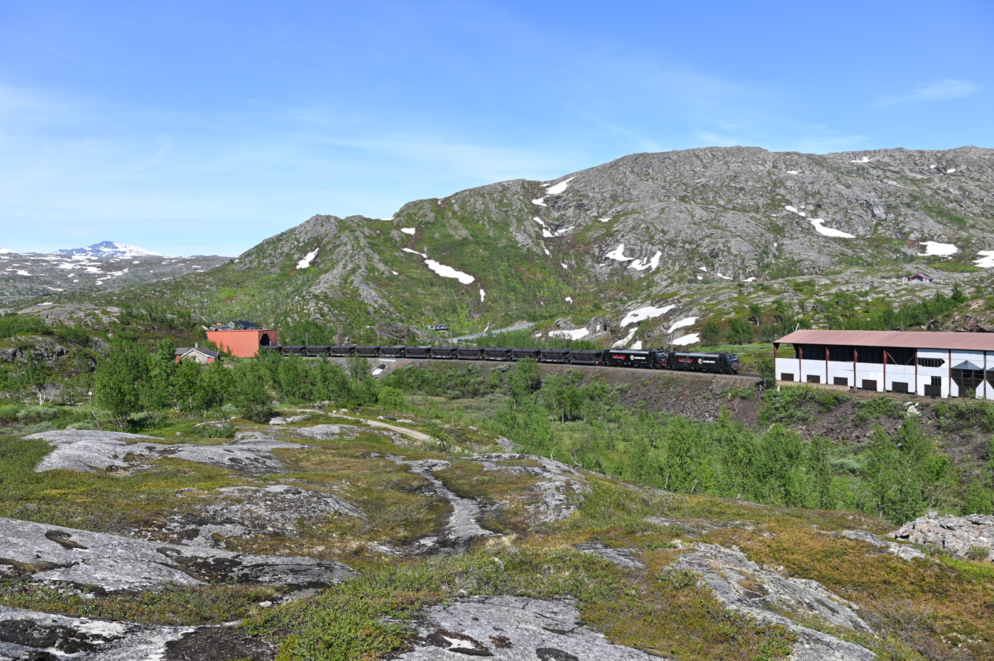 Neben den Zügen von LKAB gibt es auch noch ein zweites Unternehmen, welches auf der Erzbahn sein Erz nach Narvik fährt. Die Eisenerzmine in Kaunisvaara nahe der Grenze zu Finnland wird seit einigen Jahren wieder von Kaunis Iron betrieben. das in Kaunisvaara geförderte Erz wird erst mit dem LKW über 100 km durch Lappland zum Verladebahnhof nach Svappavaara gefahren. Von dort geht es mit zwei Zügen am Tag nach Narvik wo auf Schiffe umgeladen wird. Am Nachmittag des 30.06.2022 ist ein leerer Kaunis-Zug kurz vor Bjørnfjell in Richtung Schweden unterwegs. Gezogen werden die Züge von zwei oder drei Loks der BR 185.