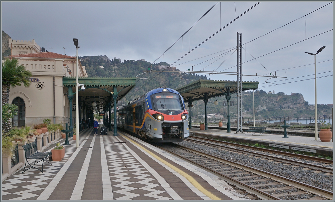 Pünktlich wie die Eisenbahn...
Nachdem ein schwerer Wintersturm vom 20. bis 22. Januar besonders die Nordostküste von Sizilien verwüstet hatte, musste auf dem Abschnitt Messina - Taormina der Zugsbetrieb eingestellt werden. RFI musste an etlichen Küstenabschnitten die Infrastruktur wieder herrichten und dies sollte bis am 6. März dauern. Unsere Anreise nach Taormina-Giradini (bzw. Naxos) war schon lange vorher für den 7. März geplant und aus Erfahrungen bei  anderen Bahnen, war ich etwas skeptisch ob der Termin für den 7. März auch eingehalten werden konnte. 
Doch pünktlich wie die Eisenbahn fahren seit dem 7. März wieder Züge zwischen Messina und Taormina! 

Der FS Treniatila ETR 104.100 verlässt den Bahnhof von Taormina-Giardini. Der Triebzug ist als Regionalzug 12977 von Messina nach Catania Aeroporte Fontanarossa unterwegs.

7. März 2026