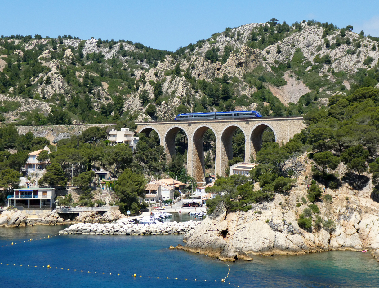 Regionalzug von Marseille nach Miramas auf dem Viaduc de Méjean in der wundervollen Landschaft an der Cote Bleue. Diese Strecke verläuft über viele Brücken und durch mehrere Tunnels grösstenteils dem Meer entlang. Das Foto wurde von einem Wanderweg aus gemacht. Méjean, 3.6.2024