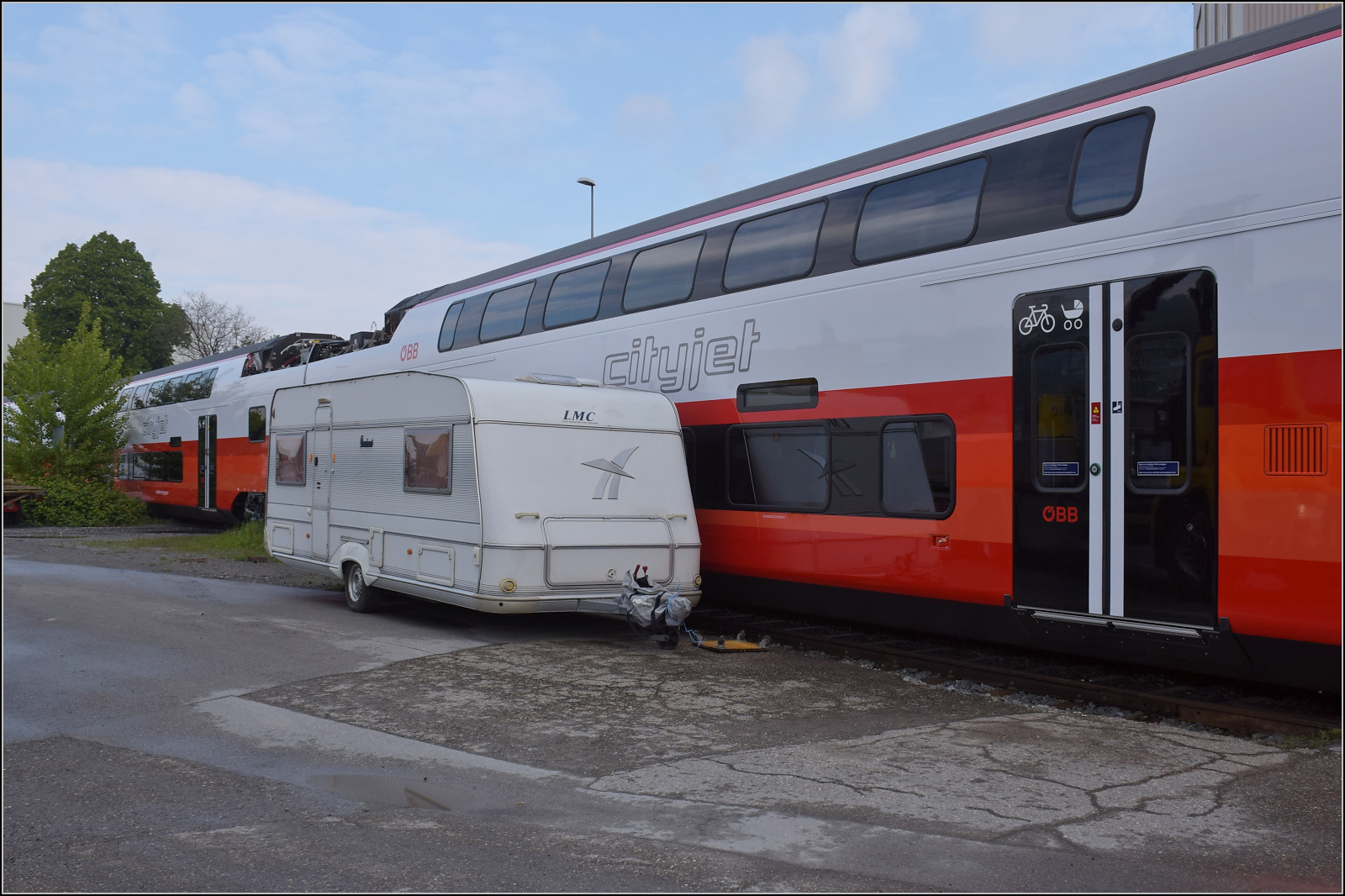 Rollout des ersten Kiss für die ÖBB. 

Ziemlich knapp geht es erst mal an einem ungünstig abgestellten Wohnwagen vorbei, hier für den Zwischenwagen 7034 301. St. Margrethen, April 2024.
