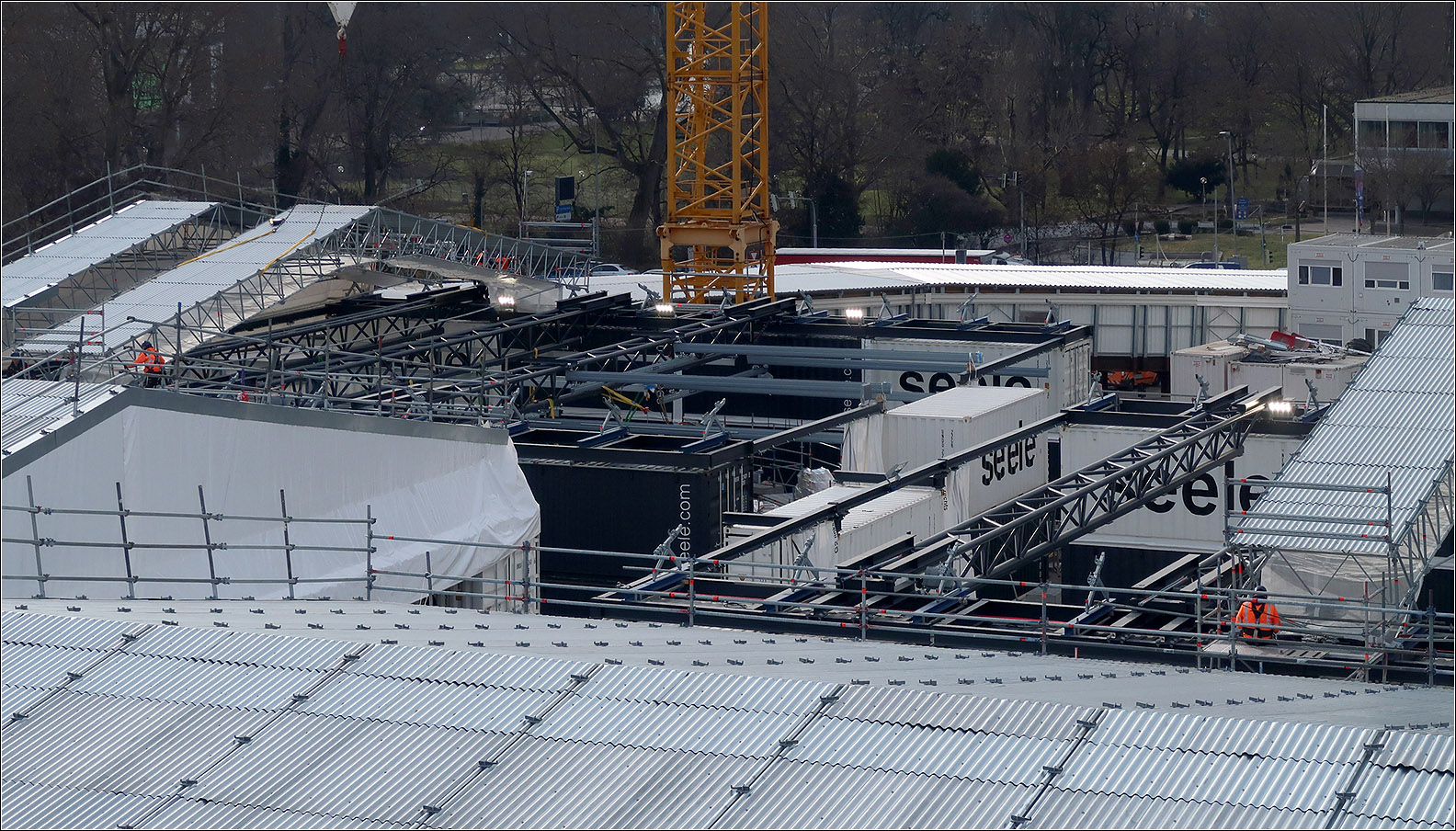 Schritte beim Einbau der Lichtaugen-Verglasungen -

Zunächst werden die Lichtaugen mit einem begehbaren Netz geschlossen, da die Arbeiten von oben her erfolgen da darunter der Ausbau der Bahnhofshalle weitergehen muss. Dann werden Container neben den Lichtaugen auf das Bahnhofsdach gestellt. Zwischen diese werden Gitterträger gespannt, an die dann die stählernen Segmente des Lichtauges mit Schwertastgurten gehängt werden, die zuvor mit den großen Baukränen eingehoben werden. An den Gurten hängend können dann die Segmente ausgerichtet werden. Das Ganze wird dann zeltartig Überdacht (was hier im Bild gerade im Gange ist) und unter diesem Schutz werden dann die Segmente an ihre Positionen gebracht und verschweißt. Die einzelnen Gläser werden danach mittels einer Kranbahn an ihre Stelle gebracht und eingebaut.

Stuttgart Hauptbahnhof, 30.01.2024 (M)
