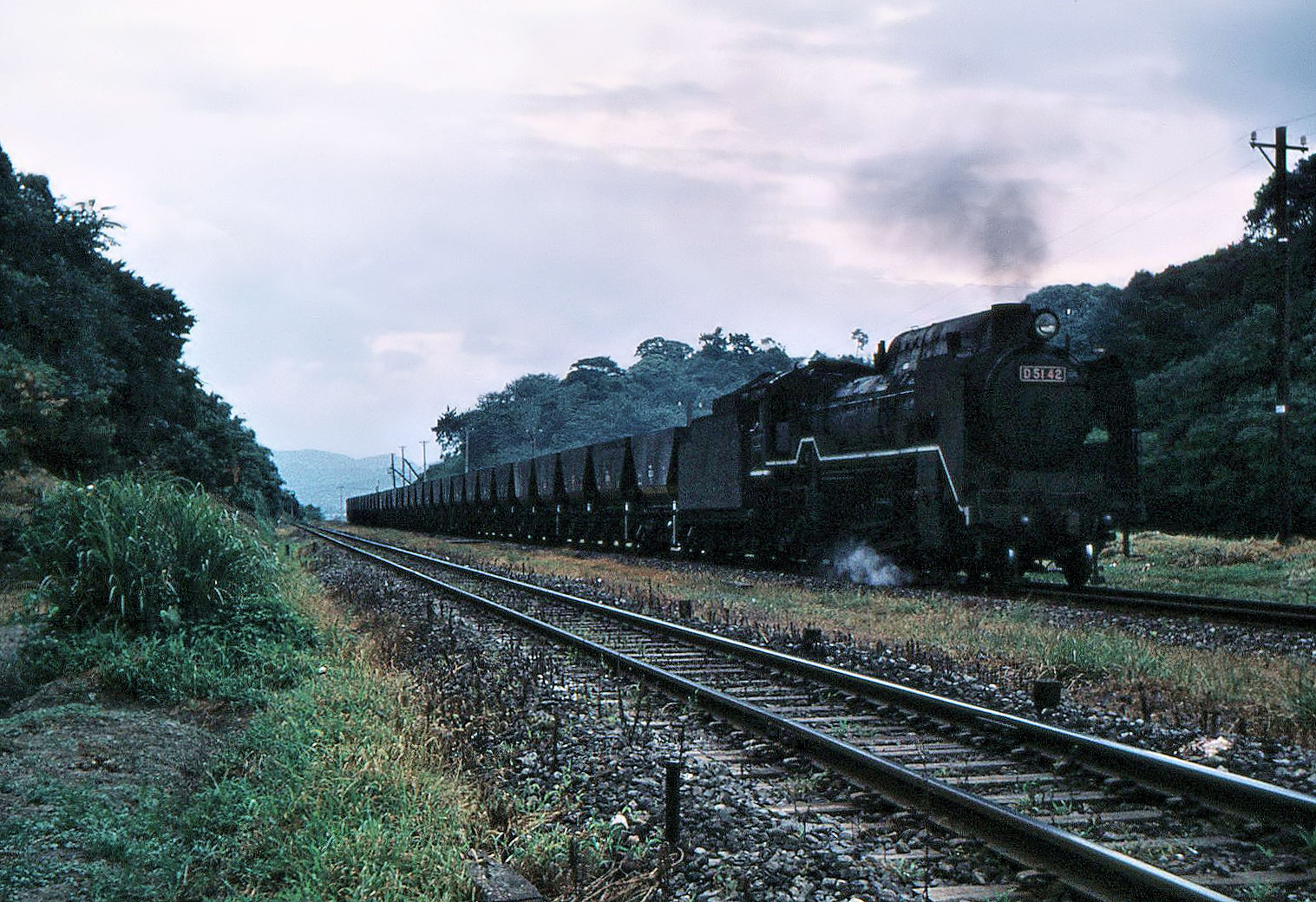 So sah eine Bahnstrecke im Chikuhô-Gebiet aus am 9. August 1972. Ein schwerer Kohlezug, geführt von der Dampflok D51 42, fährt durch Chikuzen Habu. 