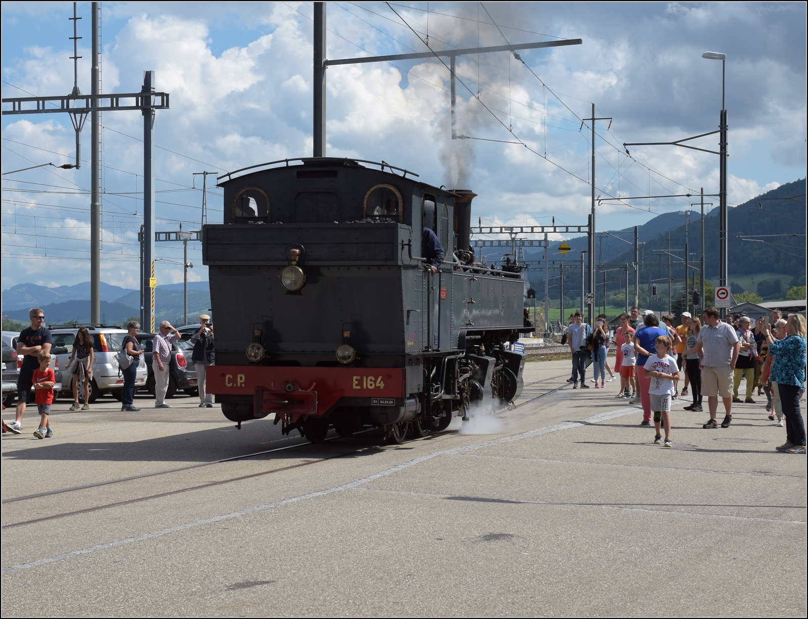 Train a vapeur de Franches-Montagnes von La Traction.

Als das Wasserfassen von CP E164 fertig ist, macht die Fotowolke auch Platz, die vielen schaulustigen Dampfzugpassagiere auch. Glovelier, September 2022.