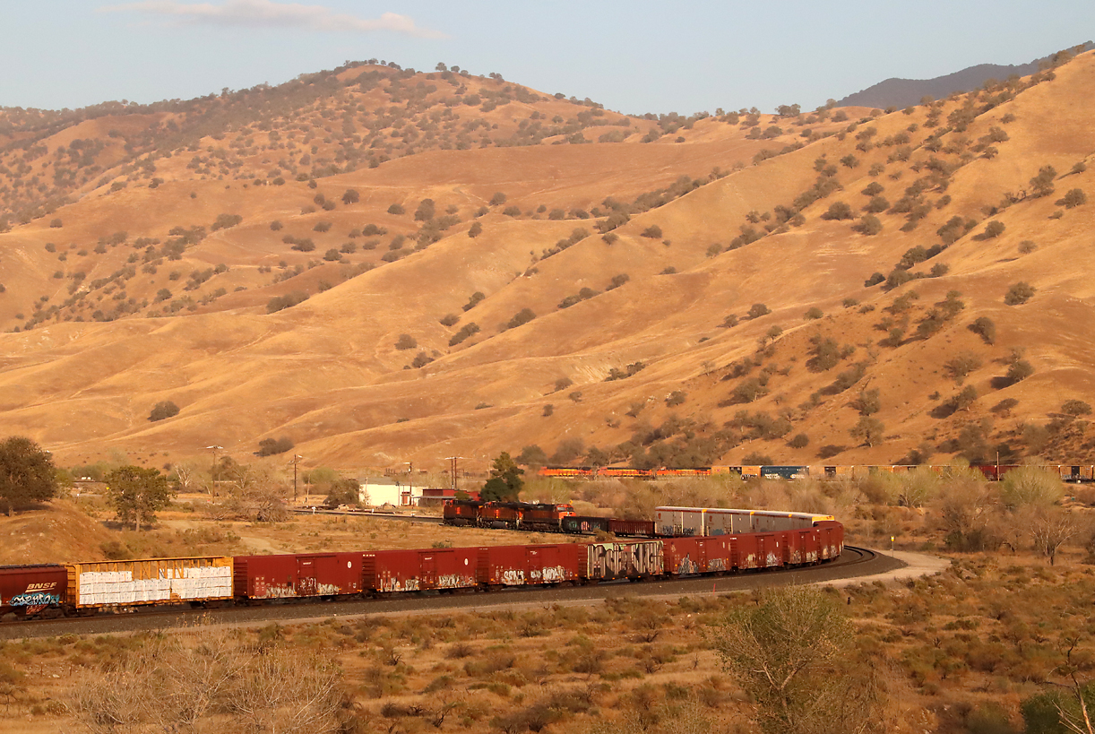 Um 18.54 Uhr noch knapp in der Sonne: Der bergwärts fahrende Güterzug im Vordergrund wartet bei Caliente auf dem doppelspurigen Abschnitt den Gegenzug ab, der sich im Hintergrund auf dem Einspurabschnitt talwärts bewegt. Caliente, CA, 26.9.2022