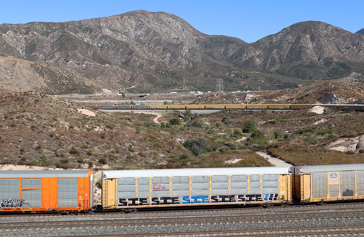 UP-Autozug fährt in der Sullivan's Curve talwärts Richtung San Bernardino. Die beiden Loks sind in der Bildmitte ganz hinten zu sehen. Für Trainspotters ist das Fotografieren am Cajon Pass übrigens recht einfach, die Züge fahren höchstens mit geschätzten 30 km/h berg- und talwärts. Cajon Pass, CA, 22.9.2022