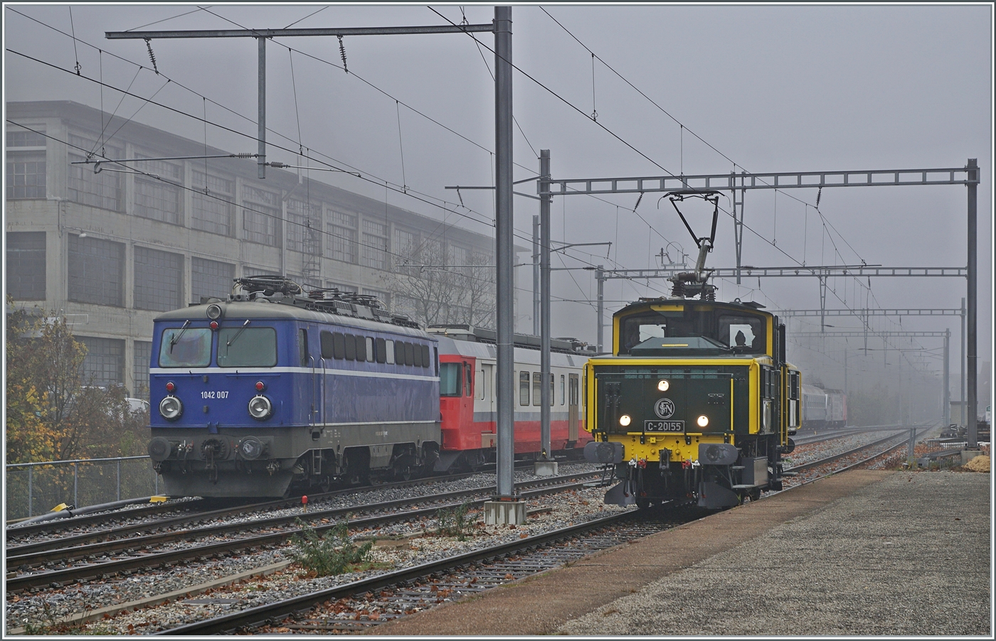 Wenn eine ex SNCF Lok eine ex ÖBB Lok trifft, ist dies ein Bild wert, selbst bei diesem Nebelwetter. 

Die SNCF C 20155 UIC N° 97 85 1 932-0 (ex SBB Ee 3/3 II 16515, ex SNCF C 20155) führt im Rahmen der offen Tür in Balsthal Führerstandsfahrten auf der OeBB Strecke Balsthal - Klus - Balsthal aus und erreicht den Bahnhof Klus, während die ex ÖBB 1042 007 (heutige UIC Nummer 91 85 1042 007-1) hier abgestellt ist. 

8. November 2025