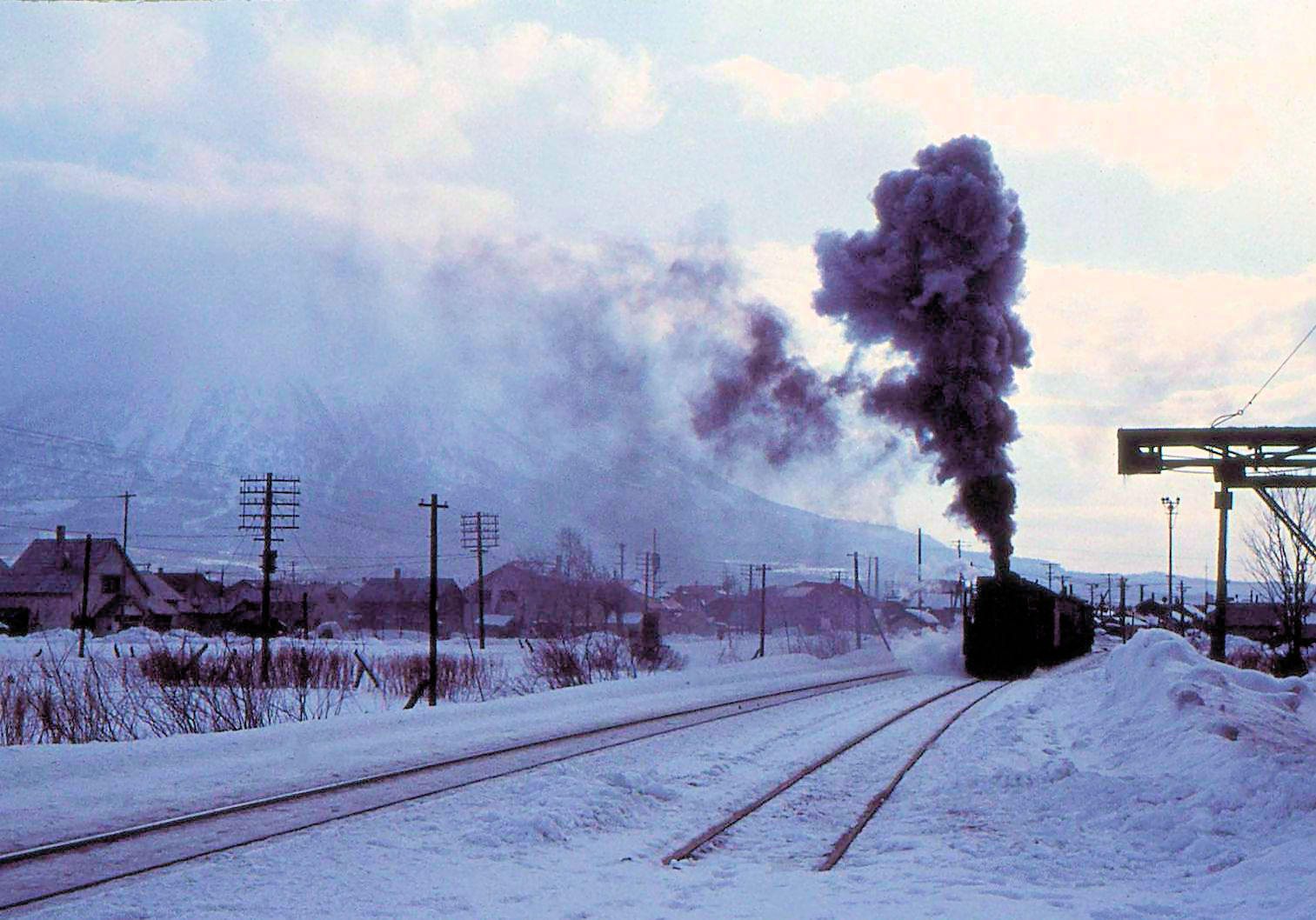 Winter in Kutchan, als noch mit Dampf gefahren wurde. Im Hintergrund der Vulkan Yôteizan. Dampflok Serie 9600 Nr. 79615. 26.Dezember 1971 
