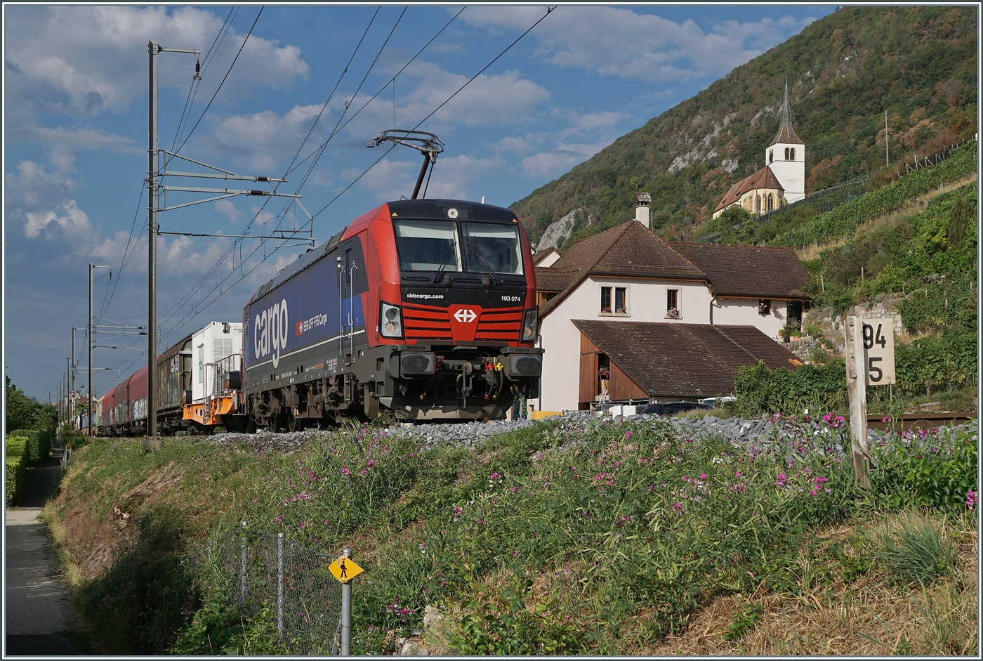 Ziemlich Bild f�llend zeigt sich die von SBB Cargo angemietete 193 074 mit ihrem langen G�terzug bei Ligerz bei Kilometer 94.5. Der Zug ist in Fahrtrichutng Biel/Bienne unterwegs. Trotz der Dominaz des Zuges fand die bekannte Kirche von Ligerz auf dem Bild doch noch Platz.

24. August 2026