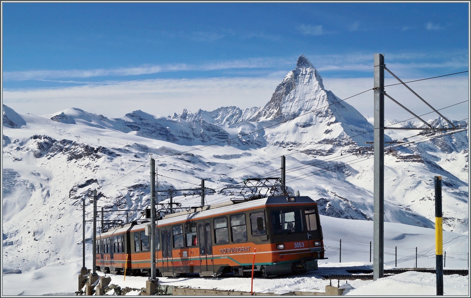 Zwei GGB Bhe 4/8 mit dem Bhe 4/8 3053 an der Spitze, erreichen von Zermatt her kommend in Kürze ihr Ziel Gornergrat. Im Hintergrund das Matterhorn, welches auch die Grenze zu Italien markiert; dahinter liegt das Aostatal. 

27. Februar 2014 