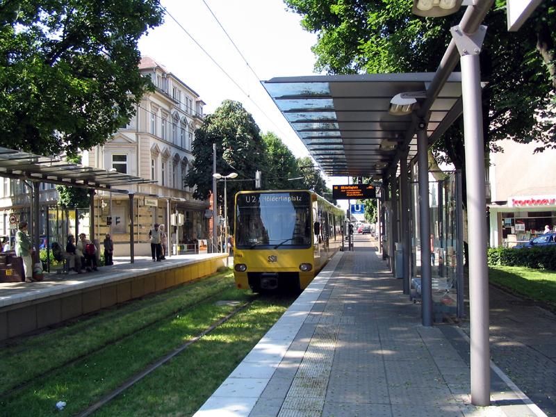 . Sorgfältig geplant -

Die Hochbahnsteige der Haltestelle Daimlerplatz in Bad Cannstatt wurden in das Oval des Kreisverkehrs eingefügt. Die Gleise wurde etwas abgesenkt, die Bahnsteige zum Platz hin mit Böschungen in das Grün eingefügt. Dieser Teil des 2er wurde am 22.6.2002 auf Stadtbahnbetrieb umgestellt.

2004 (J)