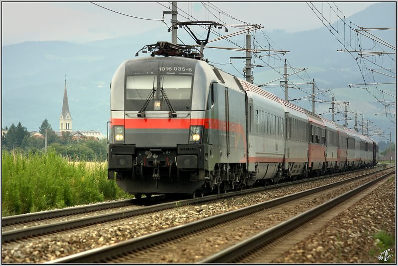 1016 035 im Railjet Vordesign fhrt mit EC 631   Alpen Adria Universitt   von Wien nach Villach.Im Hintergrund ist die Zeltweger Stadtpfarrkirche zu sehen.
Zeltweg 13.07.2008