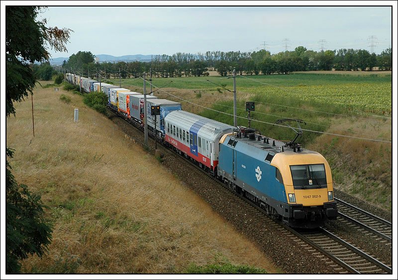 1047 002 mit einer RoLa Richtung Osten unterwegs, aufgenommen am 22.7.2007 kurz vor Gramatneusiedl.