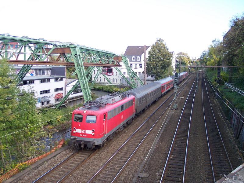 110 201 ist am 21.10.04 mit einem Zug der Linie RB 48 in Wuppertal-Oberbarmen neben der berhmten Schwebebahn unterwegs. Am Ende des Zuges luft eine 111er abgebgelt mit.
