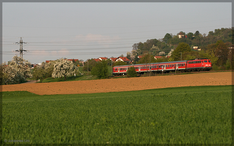 110 418-1 hat am wunderschnen Frhlingsabend des 21.04.2009 gerade mit ihrer RB aus Donauwrth ihren letzten planmigen Halt in Goldshfe hinter sich gelassen und nhert sich nun mit voller Fahrt dem Zielbahnhof Aalen. Hier durchfhrt der Zug gerade den Teilort Hofen.