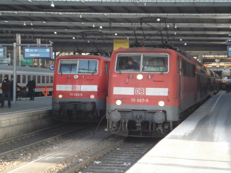 111 067-5 wartet am 03.01.09 auf Ausfahrt aus Mnchen Hbf mit Ihrem RE Richtung Salzburg, whrend die Schwestermaschine 111 024-6 soeben aus Augsburg eingetroffen ist, wohin sie nach einem kurzen Aufenthalt in der bayerischen Landeshauptstadt wieder zurckkehren wird.