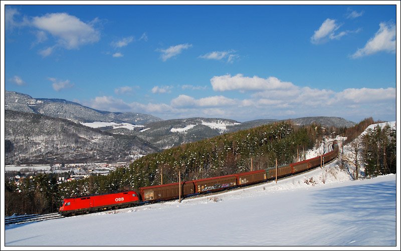 1116 024 mit ihrem Gterzug bei der Talfahrt der Semmering Nordrampe am 21.3.2009 von der Steinbauer Wiese aus aufgenommen. Im Hintergrund sieht man die Ortschaft Schlglmhl.