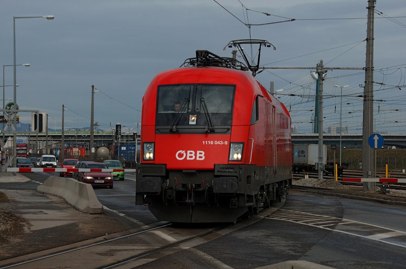 1116 043 berquert mit ihrem Containerzug den Handelskai. Die Aufnahme entstand am 28.02.2009.