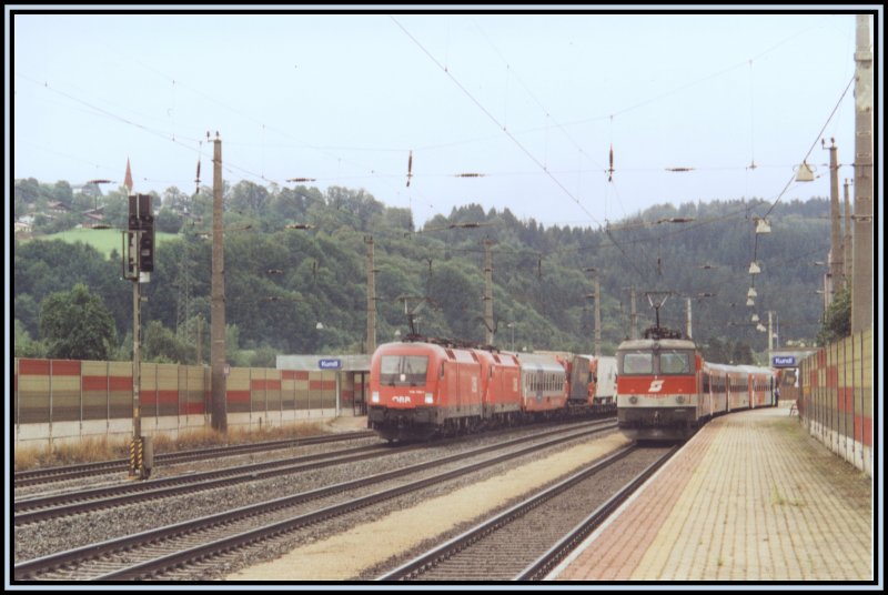 1116 066 und eine Schwestermaschiene bringen im Sommer 2004 einen RoLa-Zug von Wrgel nach Trento. Aufgenommen in Wrgel-Kundel.
Auf dem Nebengleis wartet die 1144 235 auf die Weiterfahrt nach Rosenheim.