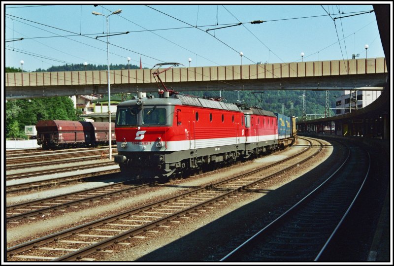 1144 202 und eine Schwestermaschiene warten auf die Abfahrt zum Brenner. Am Zugschluss schiebt 182 007 nach. Aufgenommen im Juni 2005 in Kufstein.

