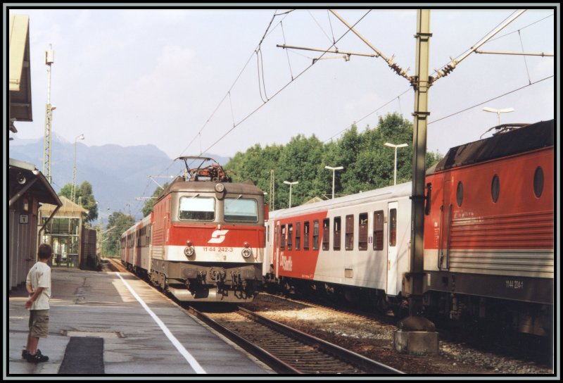 1144 242 rollt im Sommer 2003 mit einem Regionalzug von Rosenheim nach Innsbruck, in den Bahnhof Kiefersfelden ein. Auf dem Nebengleis wartet die 1144 224 mit ihrem Regionalzug nach Rosenheim auf die Abfahrt.