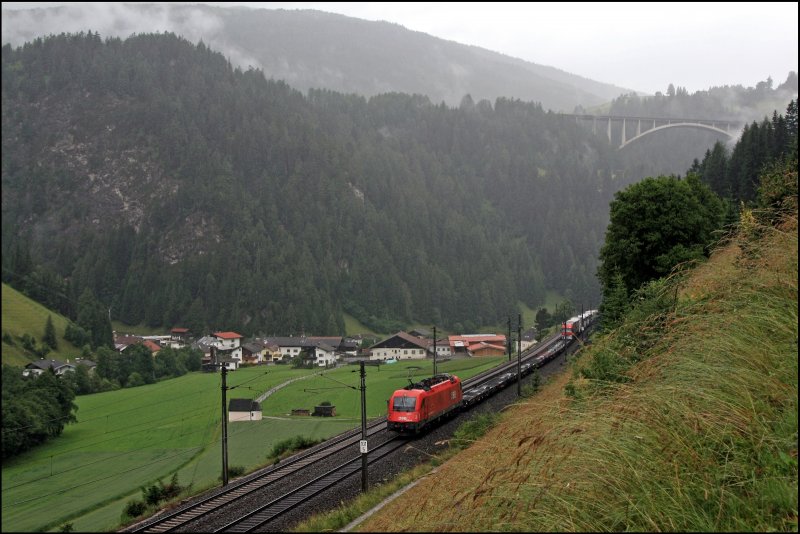1216 016 (E190 016) bremst bei St.Jodok eine RoLa Richtung Steinach i.Tirol. Im Hintergrund erkennt man die ussere Nsslachbrcke (Gesamtlnge 358,00 m; Bogenspannweite 180,00m). (07.07.2008)
