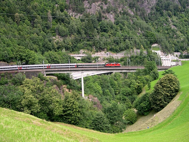125 Jahre Gotthardbahn - Zwischen Intschi und Amsteg berqueren die Zge die Intschitobelbrcke. Die Brcke wurde 1972 neu gebaut und besteht heute aus zwei eingleisigen Beton-Hohlksten. Zwischen den beiden Fahrstraen fr die Zge befindet sich ein Fussweg, der aber leider nicht in den  Wanderweg Gottardo  integriert ist. Die Brcke berquert am 08.07.2007 EC 170 Mailand - Zrich, gezogen von einer Lok der Reihe Re 4/4. An der Spitze ist wieder ein Verstrkungswagen fr eine Gruppenreise eingestellt. Verstrkungswagen fr Gruppen sind in der Schweiz alltglich, in Deutschland jedoch zur Ausnahme geworden.