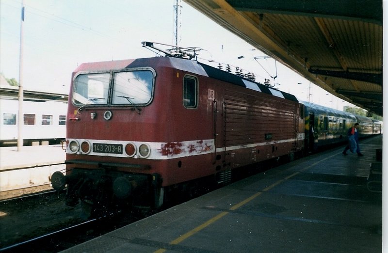 143 203 ist im Juli 1998 mit den Kurswagen aus Wolgast Hafen fr den Urlaubsexpress nach Dsseldorf in Stralsund angekommen.Auf der gegenberliegenden Bahnsteigseite stande bereits der Zug von Rgen mit der 103 220(Bild 237567).Beide Wagenteile vereinigten sich in Stralsund.