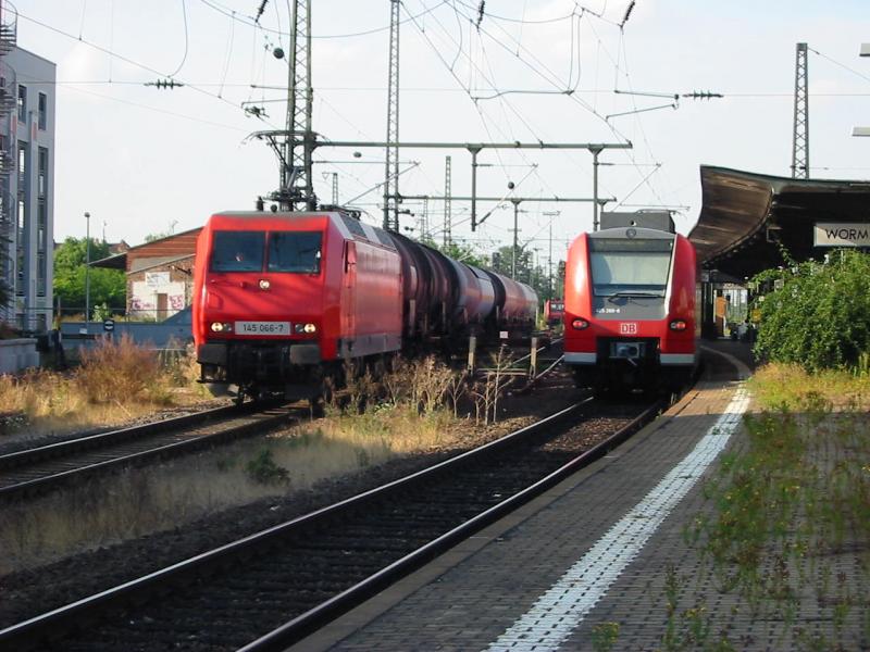 145-066 mit ihrem kurzen Kesselwagenzug verlsst am 11.8.2005 dem Wormser Hbf daneben 425-269.