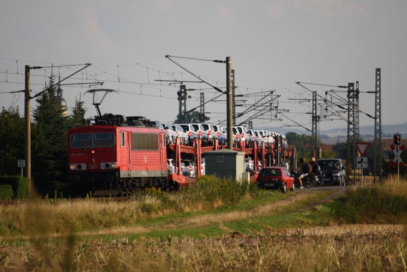 155 113 zieht einen Zug neuer Skodas in Richtung Riesa, hier am Bahn�bergang in Jessen, 06.08.09