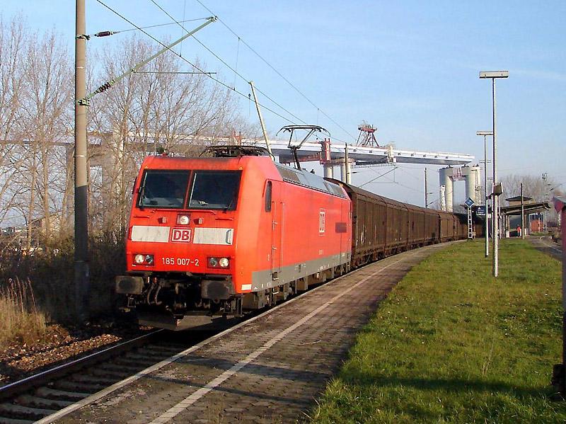 185 007-2 durchfhrt mit einem Gterzug den Bahnhof Stralsund-Rgendamm. Im Hintergrund ist ein Teil der neuen Sundquerung zu sehen. (am  01.12.05) 