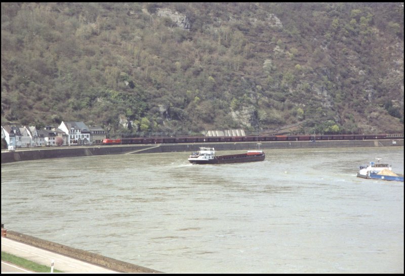 185 229 bringt ihren Kohlezug ber die Rheinstrecke nach Sden, wrend auf dem Rhein ein Transportschiff nach Norden fhrt. Aufgenommen bei Boppard-Hirzenach.