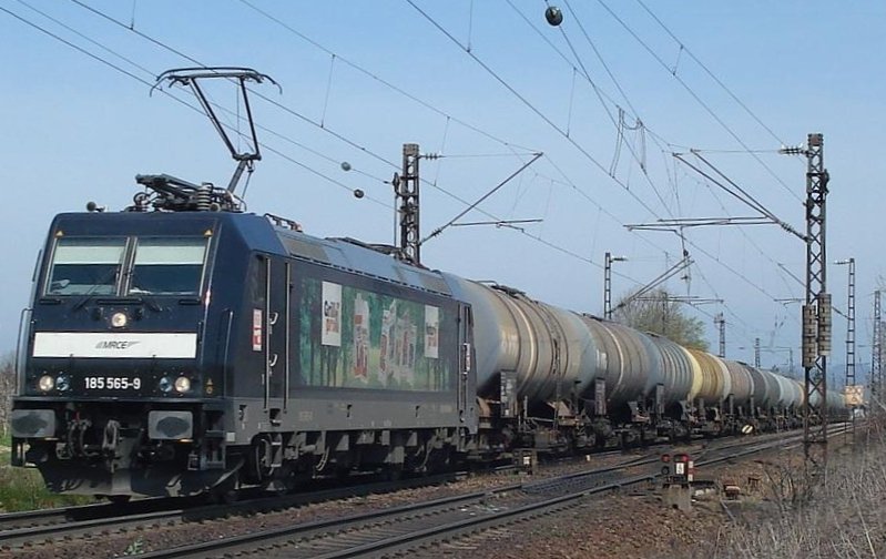 185 565 der MRCE, derzeit vermietet an HGK und zur Zeit die einzigste schwarze der HGK, mit Teilreklame f�r  Heizprofi  (einmal Grillkohle, einmal Brikett, je nach Seite verschieden) mit einem �ler bei Denzlingen. Sie hat den Zug gemeinsam mit 185 526 nach Karlsruhe gebracht und ist nun alleine auf dem Weg nach Basel. Hier passierte sie am 5.4.2007 Denzlingen nahe Freiburg auf der KBS 702.