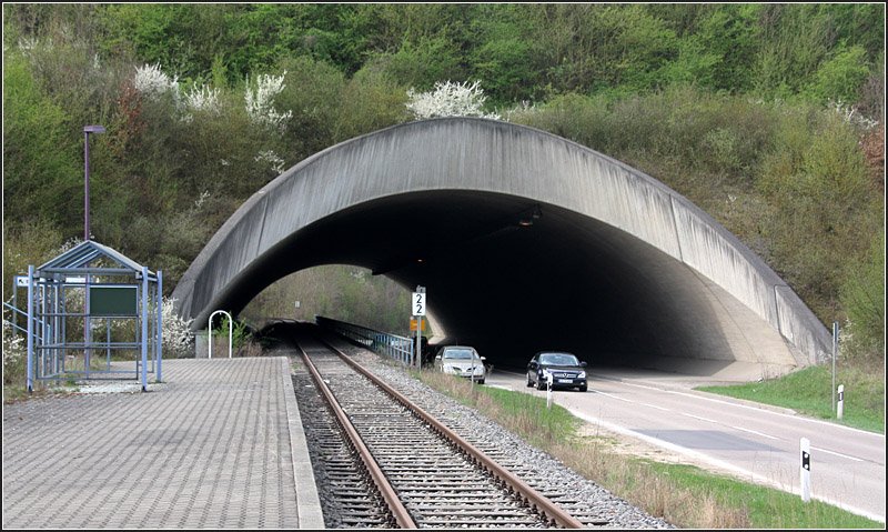 1991 wurde dieser Haltepunkt  Vaihingen WEG  am neuen DB-Bahnhof Vaihingen eröffnet. Der Haltepunkt ist Teil der sogenannten Vaihinger Stadtbahn, einer Nebenbahn, die die eigentliche Stadt Vaihingen mit der Hauptbahn (Westbahn) am Bahnhof Vaihingen Nord verband. 2002 wurde der Betrieb dieser Nebenbahn eingestellt, da der neue Vaihinger Bahnhof doch näher an der Stadt liegt. Ich könnte mir hier gut einen AVG-Stadtbahnbetrieb vorstellen, von Vaihingen nach Bietigheim, der diese beiden Städte verbindet, mit zusätzlichen Haltepunkten in Sersheim und Großsachsenheim.  Der gewaltige Bahndamm des neuen DB-Bahnhofes machte dieses tunnelähnliche Bauwerk erforderlich. 

12.04.2009 (M)