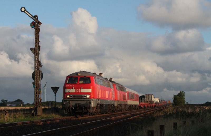 218 162 und eine Schwester rollen bei den ersten Sonnenstrahlen des 17. August vom Hindenburgdamm hinab in den Bahnhof Klanxbll.
