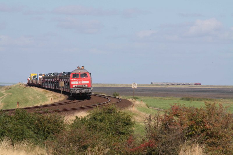 218 381 steht mit einem Autozug am 14.8.2009 auf freier Strecke am Ende des Hindenburgdammes bei Morsum, whrend im Hintergrund ein IC Richtung Festland rollt.