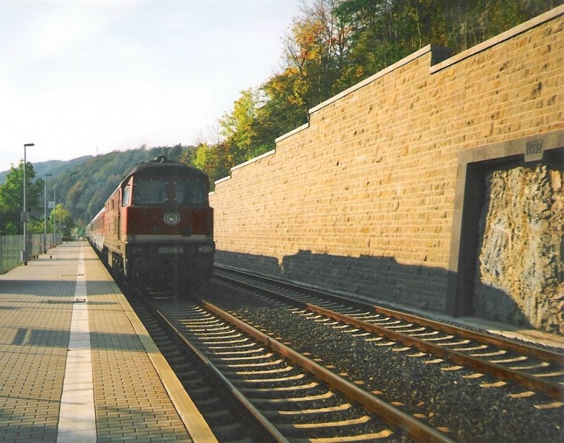 232 418-4 mit einem IC in Richtung Eisenach bzw. Dresden passiert den Haltepunkt Hrschel. Im Hintergrund, in der Mauer, wurde eine bei Umbauarbeiten im Jahre 1992 entdeckte, Millionen Jahre alte Magma-Ader freigelegt und eingerahmt. Aufgenommen an einem sptherbstlichen Abend 1993/94. (Foto Scan).