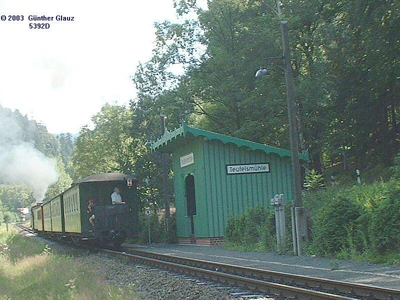 99 758 mit Personenzug verlt am 15.07.2003 die Haltestelle Teufelsmhle in Richtung Kurort Oybin. Die grne Wartehalle ist ein Nachbau nach alten Plnen der ersten von 1892.